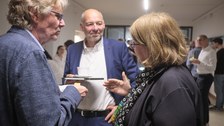 Es sind drei Gäste bei einer Festveranstaltung zu sehen, die sich unterhalten