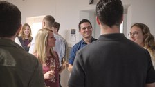 Es ist eine Gruppe von Menschen bei einer Festveranstaltung zu sehen, die sich unterhalten
