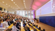 Es ist ein gut gefüllter Hörsaal bei einer Feierstunde zu sehen
