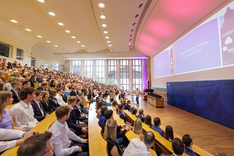 Es ist ein gut gefüllter Hörsaal bei einer Feierstunde zu sehen