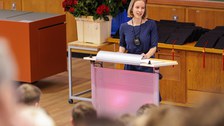 Es ist eine Absolventin zu sehen, die eine Rede hält