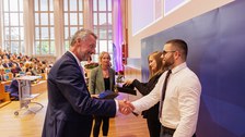 Es sind Professoren zu sehen, die Absolventen zum Abschluss des Studiums gratulieren