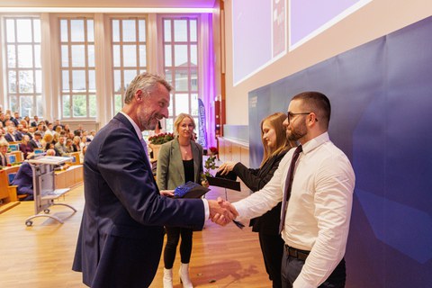 Es sind Professoren zu sehen, die Absolventen zum Abschluss des Studiums gratulieren