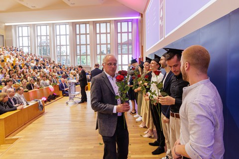 Es sind Professoren zu sehen, die Absolventen zum Abschluss des Studiums gratulieren