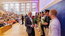 Es sind Professoren zu sehen, die Absolventen zum Abschluss des Studiums gratulieren