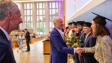 Es sind Professoren zu sehen, die Absolventen zum Abschluss des Studiums gratulieren