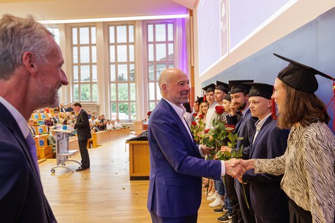 Es sind Professoren zu sehen, die Absolventen zum Abschluss des Studiums gratulieren