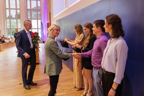 Es sind Professoren zu sehen, die Absolventen zum Abschluss des Studiums gratulieren