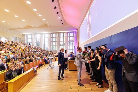 Es sind Professoren zu sehen, die Absolventen zum Abschluss des Studiums gratulieren
