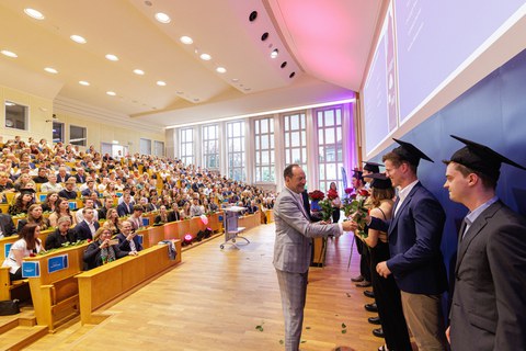 Es sind Professoren zu sehen, die Absolventen zum Abschluss des Studiums gratulieren