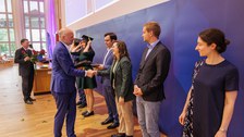 Es sind Professoren zu sehen, die Absolventen zum Abschluss des Studiums gratulieren