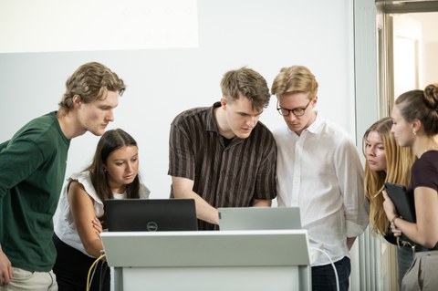 Zu sehen ist eine Gruppe Studierender an einem Laptop