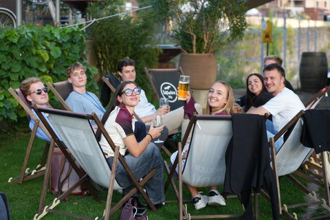 Zu sehen sind junge Menschen die in Liegestühlen sitzen