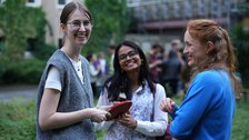 Es sind drei junge Menschen bei einem Grillfest zu sehen