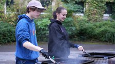 Es sind eine Frau und ein Mann an einem Grillstand zu sehen