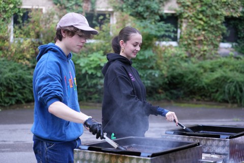 Es sind eine Frau und ein Mann an einem Grillstand zu sehen