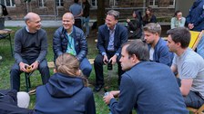 Es sind Menschen auf einem Fest zu sehen, die in Liegstühlen sitzen und sich unterhalten