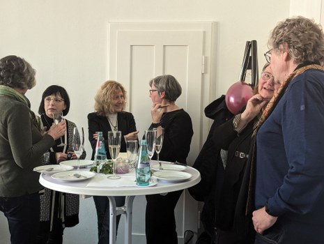 Es ist eine Gruppe von Menschen zu sehen, die sich bei einer Feier unterhalten