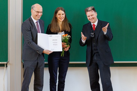 Es sind Prof. Buscher, Maria Beranek und Prof. Schefczyk zu sehen