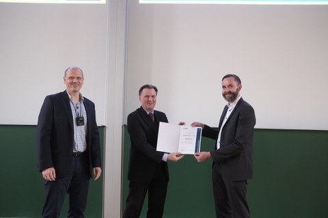 Es sind Prof. Wiener, Prof. Krancher und der Dekan bei einer Preisverleihung zu sehen
