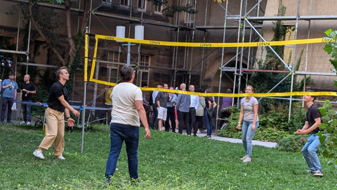 Man sieht ein Volleyballnetz mit Spielenden.