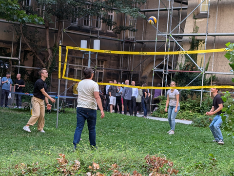 Man sieht ein Volleyballnetz mit Spielenden.