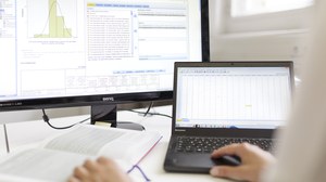 Zu sehen ist ein Laptop und ein großer Bildschirm mit dem Programm SPSS