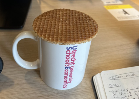 Zu sehen ist eine Tasse auf der ein Keks liegt 