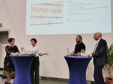 Zu sehen sind vier Menschen, die bei einer Paneldiskussion sind. 
