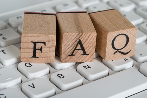 Das Foto zeigt drei Holzwürfel auf einer Tastatur. Auf den Holzwürfeln sind die Buchstaben FAQ abgebildet.