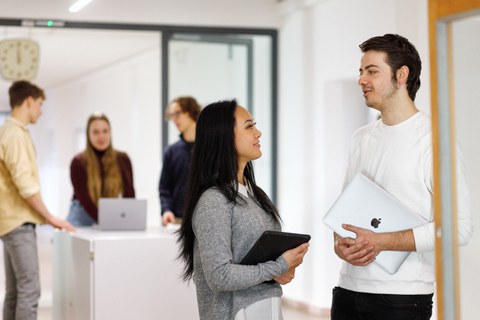 Es sind zwei internationale Studierende zu sehen, die sich unterhalten.