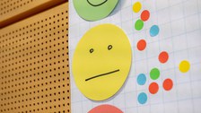 Foto zeigt ein Flipchart mit drei farbigen Smileys und kleinen bunten Kreisen darauf.