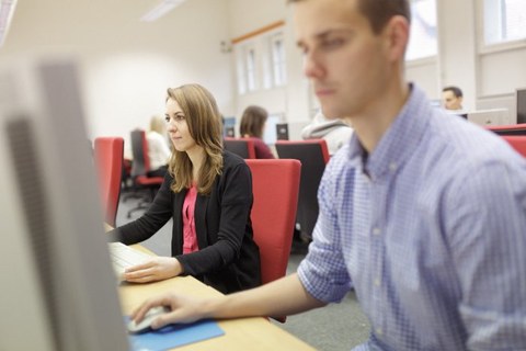 Zwei Studierende sitzen im Computerpool vor Rechnern.