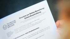 Das Foto zeigt die Hände einer Person. In diesen hält sie ein Formular mit der Aufschrift: "Hinweise zur Online-Bewerbung/Online-Einschreibung"