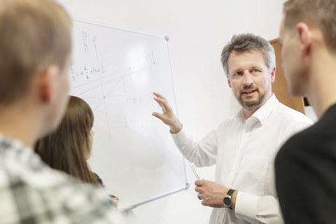 Ein Professor erklärt Studierenden wichtige Vorlesungsinhalte.