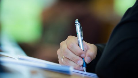 Eine unbekannte Person macht Notizen im Hörsaal