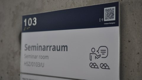 Das Foto zeigt ein Hinweisschild. Dieses sagt aus, dass es sich bei Raum 103 um einen Seminarraum handelt.