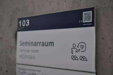 Das Foto zeigt ein Hinweisschild. Dieses sagt aus, dass es sich bei Raum 103 um einen Seminarraum handelt.