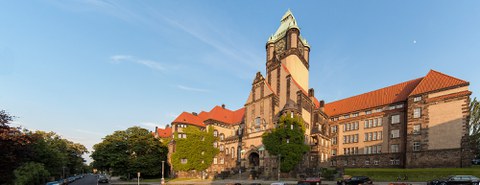 Außenansicht des Georg-Schumann-Baus der TU Dresden. Das Gebäude ist teilweise bewachsen und wirkt wie eine Burg. Besonders ist der große Wehrturm. 