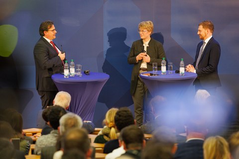 Man sieht Prof. Christian Leßmann, Prof. Veronika Grimm und Ministerpräsident Michael Kretschmer bei eine Diskussionsveranstaltung.