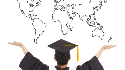 Picture of a graduate photographed from behind with a bachelor hat in front of the graphic of a world map, arms up