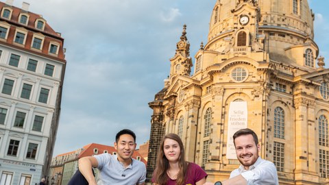 Drei Studierende sitzen vor der Frauenkirche