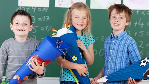 Es sind drei Kinder mit Zuckertüte zu sehen.