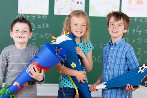 Es sind drei Kinder mit Zuckertüte zu sehen.