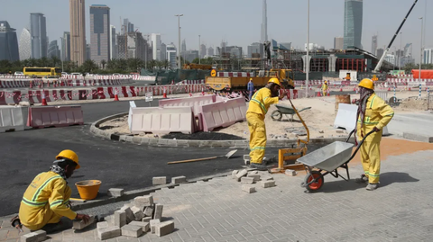 Construction workers with wheelbarrow paving a pavement