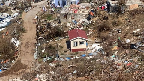 An undestroyed house in the middle of a neighbourhood in which many destroyed parts of houses lie