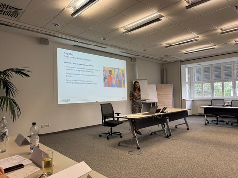Frau Garthus Niegel hält einen Vortrag vor eine Powerpointspräsentation