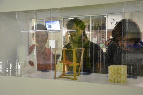 Blick auf drei Personen durch eine Vitrine mit mathematischen Modellen. 
