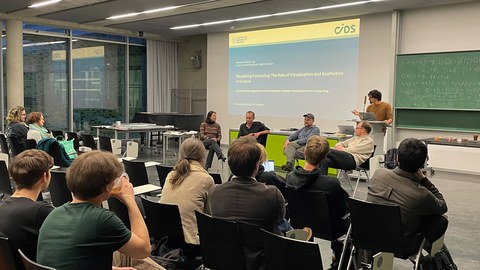 Blick aus dem Zuschauerraum auf einen Redner, der eine Präsentation vorstellt.