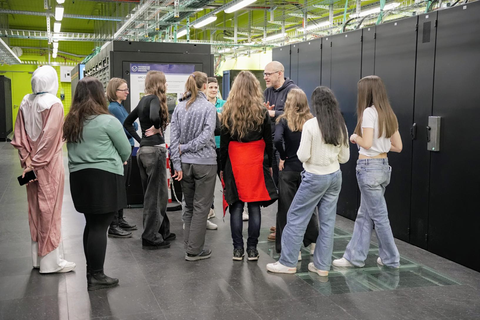 Foto. Die sieben Mädchen und vier Betreuerinnen hören Carsten Tiede gespannt bei der Führung durch das Rechenzentrum zu.